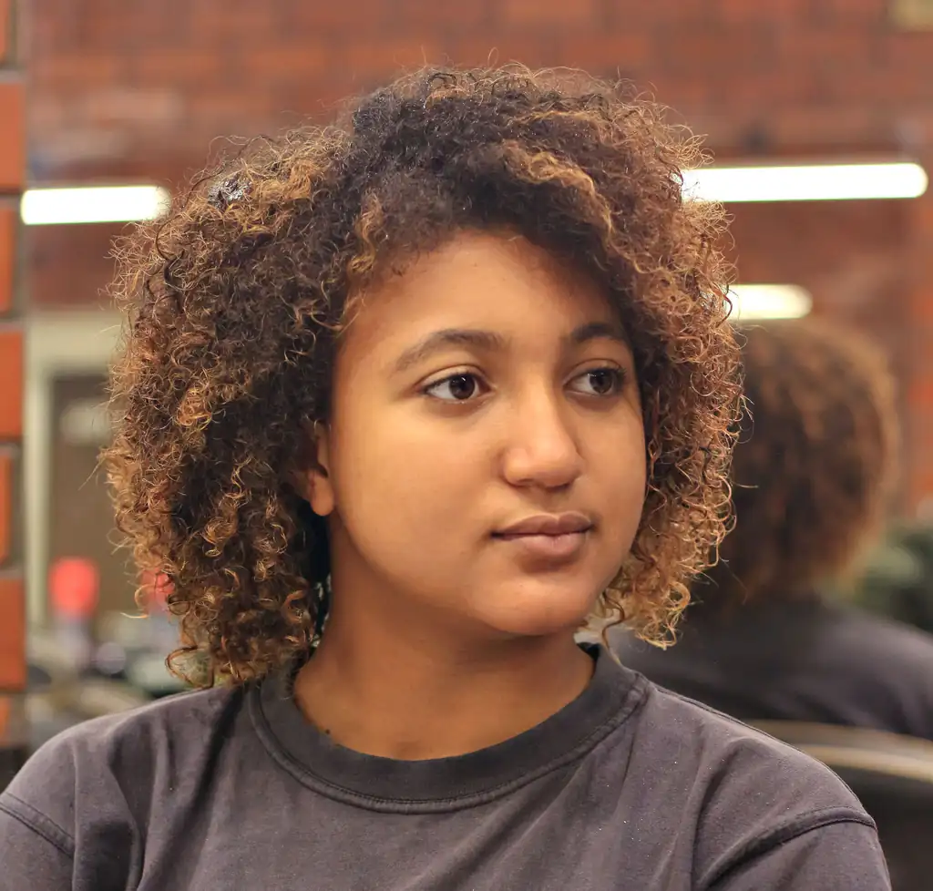 Woman with shoulder-length natural curls with caramel tones